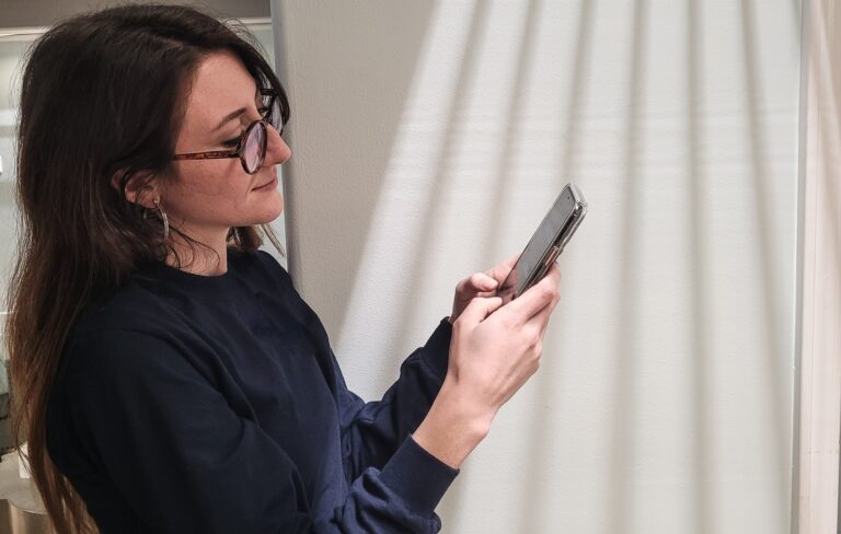 Young business professional millennial woman on mobile device video chatting with coworkers.